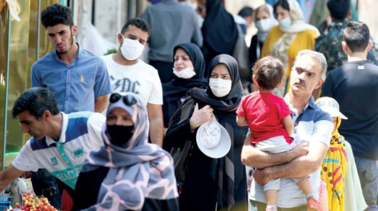 Dün Tahran’ın merkezindeki bir caddede yürüyen ve koronavirüse karşı korunmak için maske takan bazı İranlılar. (EPA)