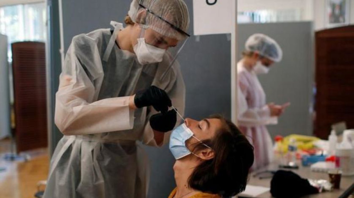 Paris'teki bir hastadan örnek alan sağlık görevlisi koruyucu kıyafet ve yüz maskesi takıyor (Reuters)
