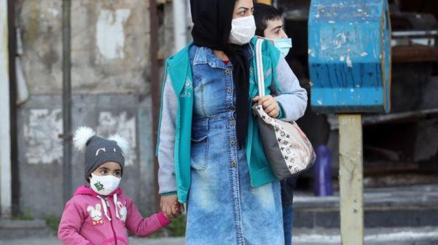 İranlı bir kadın ve iki oğlu Tahran'da yüz maskeleri takıyor (EPA)
