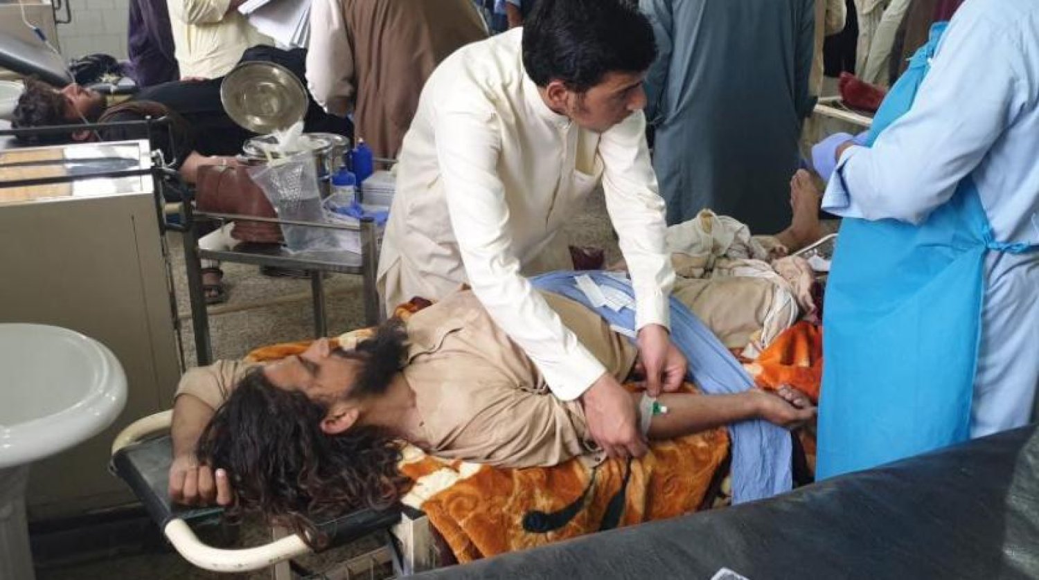 Afgan güçleri ile Taliban arasında çıkan çatışmalarda yaralanan bir kişi sağlık görevlileri tarafından tedavi edildi (AFP)