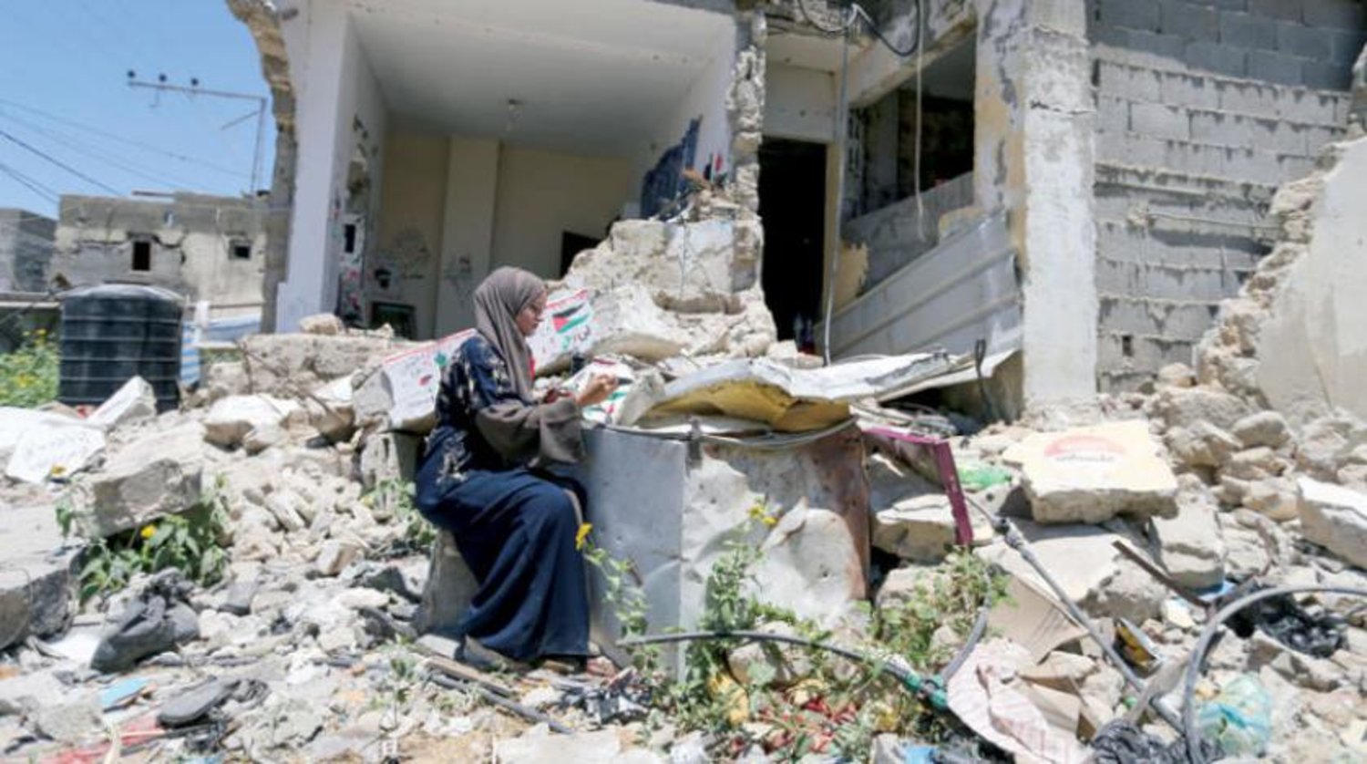 İsrail'in Refah'ta düzenlediği bombalı saldırıda yıkılan evinin enkazında resim çizen Filistinli bir kadın (Reuters)