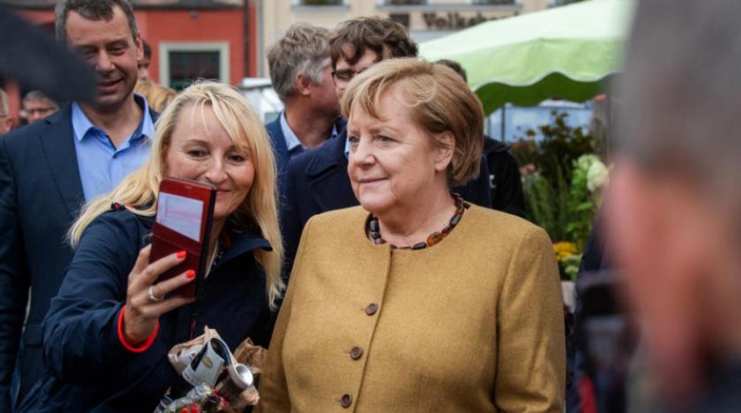 Almanya Başbakanı Angela Merkel, Greifswald’daki eski seçim bölgesinde bir fotoğraf için poz veriyor (DPA)