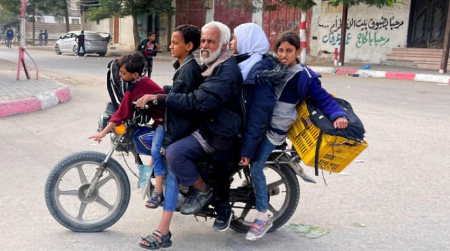 Gazze Şeridi'ndeki Refah'tan bir aile reisi okuldan dönen çocuklarını motosikletiyle taşırken (Reuters)