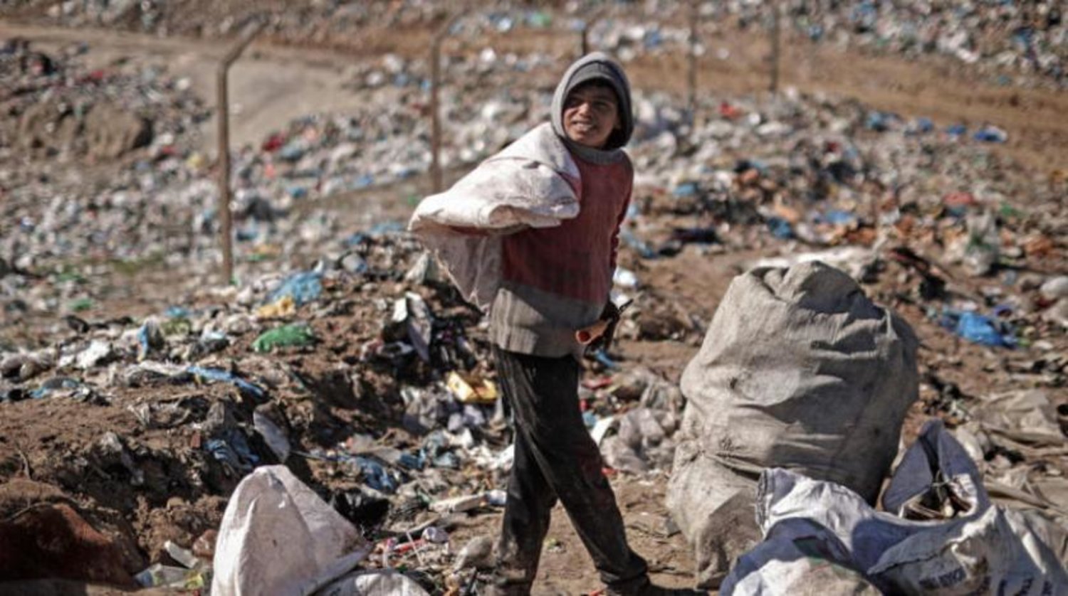 Gazze Şeridi’nin kuzeyindeki Beit Lahia’daki bir çöp alanında plastik ve demir toplayan bir çocuk (AFP)