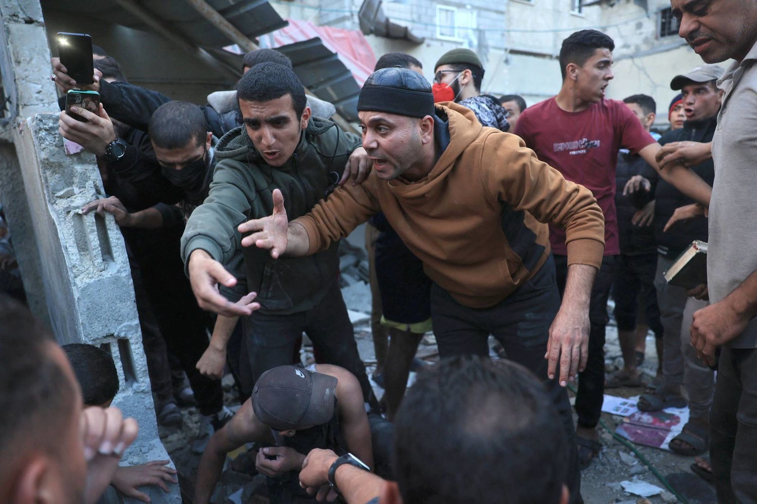 İsrail’in Gazze Şeridi’nin güneyindeki Refah’a düzenlediği bombardımanın ardından sağlık görevlileri bir binanın enkazından bir kişiyi kurtarmaya çalışırken Filistinlilerin tepkisi (AFP)