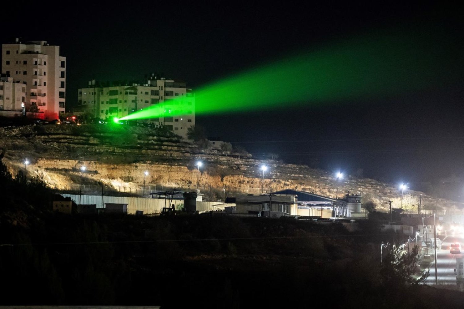 Filistinliler, işgal altındaki Batı Şeria'da Ramallah ile Beytuniya arasında bulunan Ofer askeri hapishanesine lazer tutuyor. (AFP)