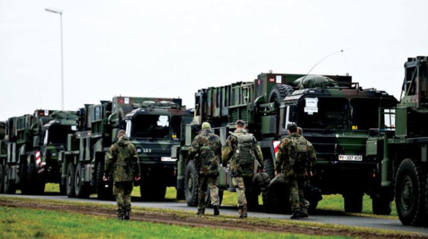 Patriot hava savunma sistemlerinin Almanya'nın Gnoien şehrinden Polonya'ya nakledildiği araçların yanında yürüyen Alman askerleri (Reuters)
