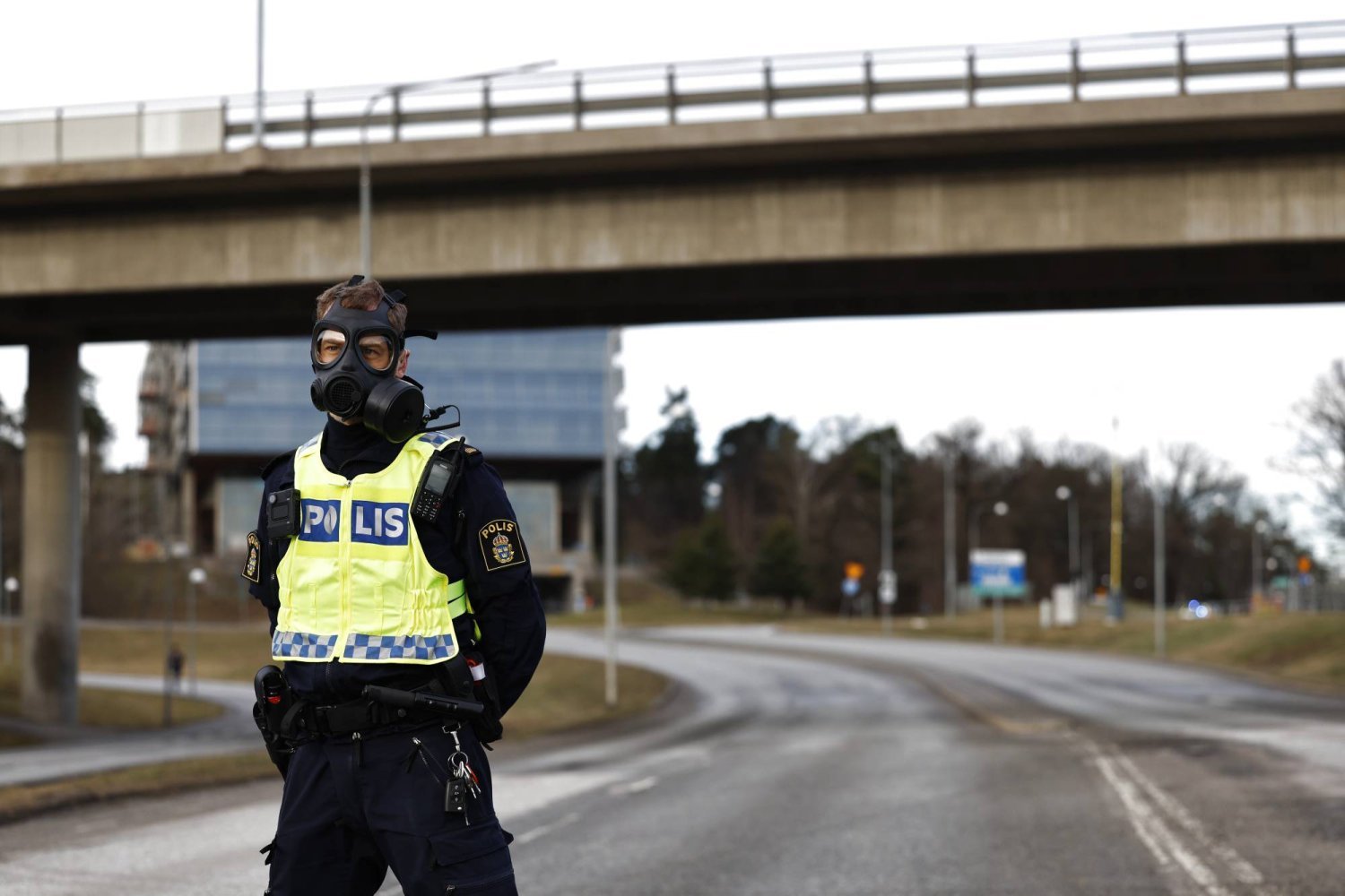 Gaz maskesi takan bir polis memuru, Stokholm'ün kuzeyindeki Solna'daki güvenlik polis merkezine giden yolda nöbet tutuyor (EPA)