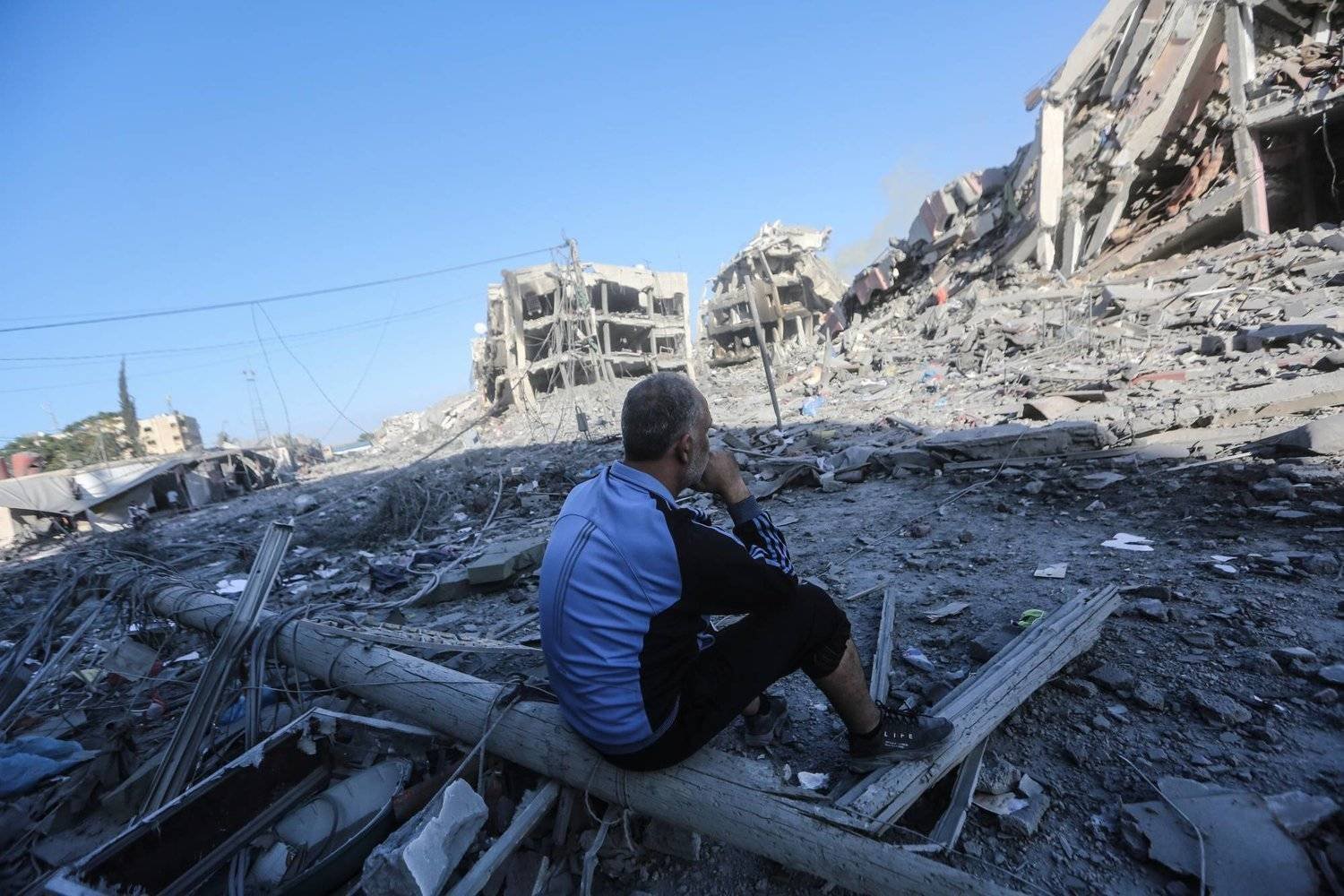 Filistinli bir adam, İsrail’in Han Yunus yakınlarındaki Zahra şehrine düzenlediği saldırının ardından yıkıntıların arasında oturuyor (DPA)