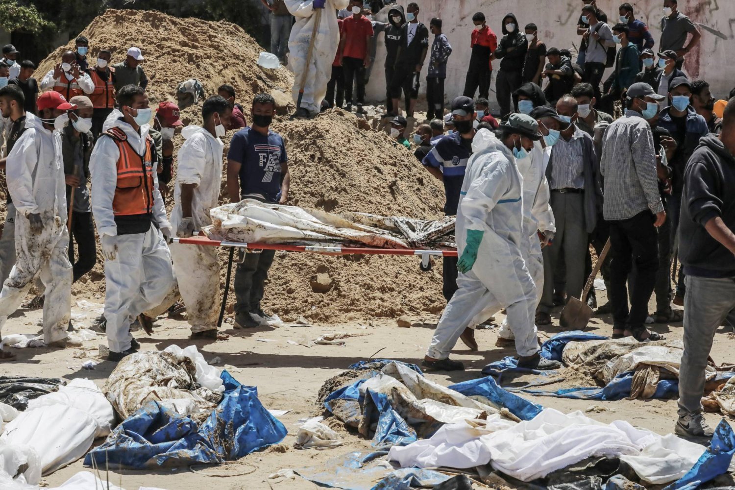 Filistin Sivil Savunma Kurumu görevlileri Gazze'deki Nasır Tıp Kompleksi'nde toplu mezarlardan çıkarılan cesetleri taşıyor. (DPA)