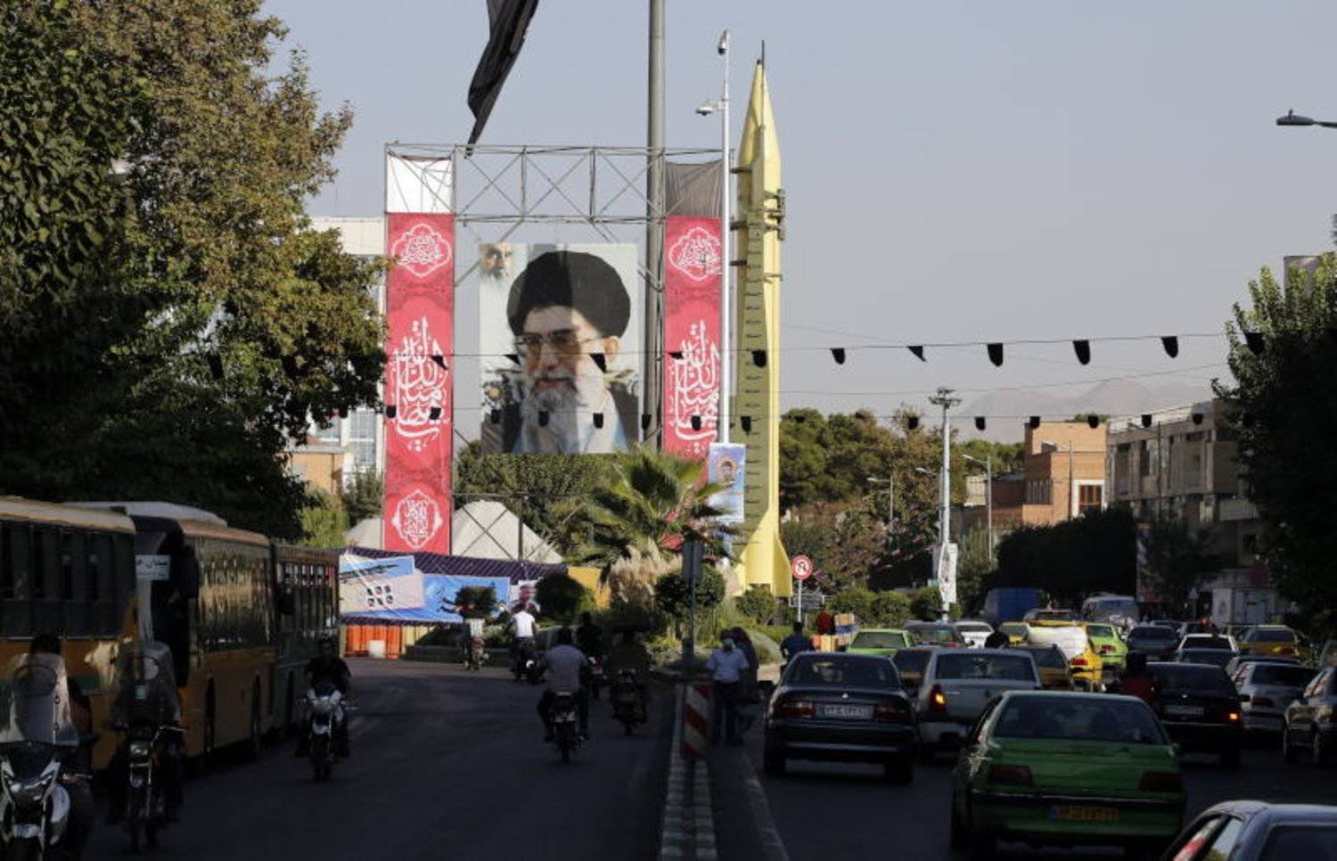 Tahran'da bir caddede Dini Lider Ali Hamaney'in resmi ve yanında sergilenen Şahab 3 karadan karaya füzesi (EPA)