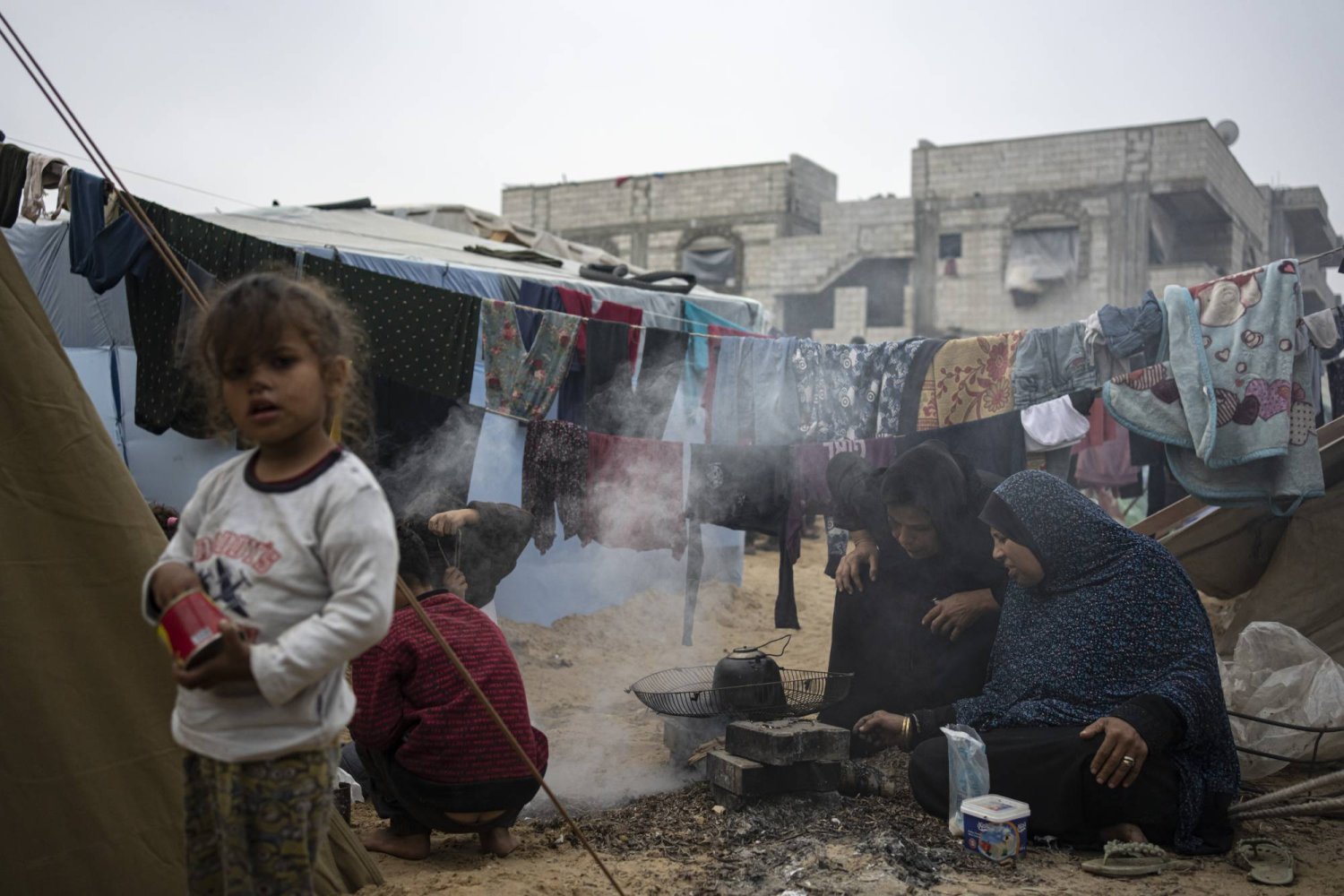  İsrail'in Gazze Şeridi'ne yönelik bombardımanı nedeniyle yerlerinden edilen Filistinliler, el-Mevasi bölgesindeki derme çatma bir çadır kampında yemek pişiriyor. (AP)