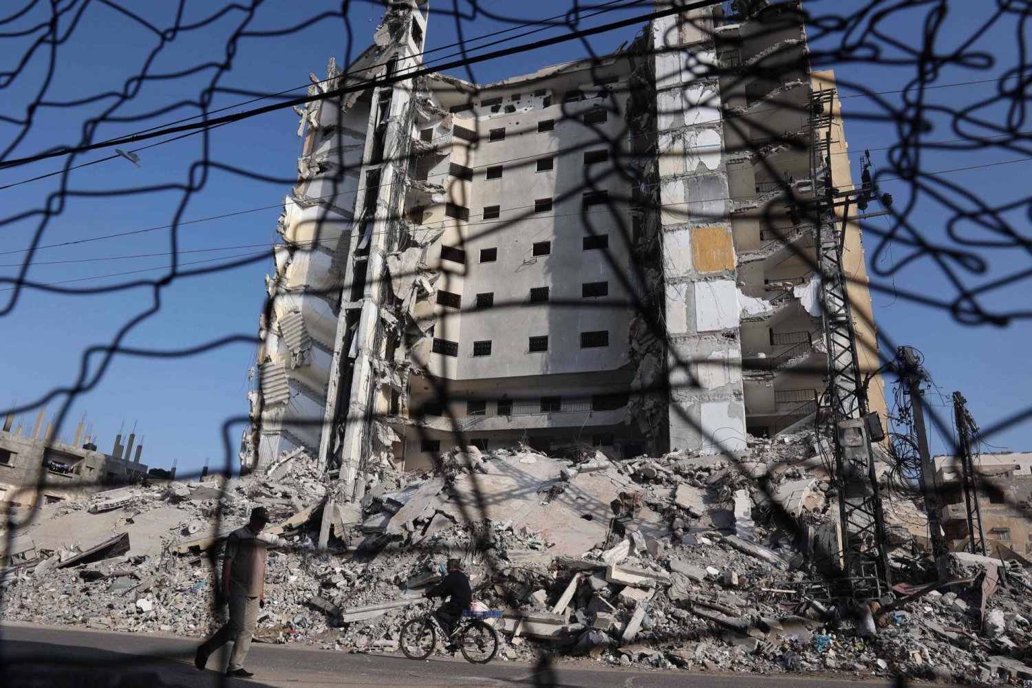 Refah'ta yıkılmış binaların önünden geçen bir Filistinli (AFP)