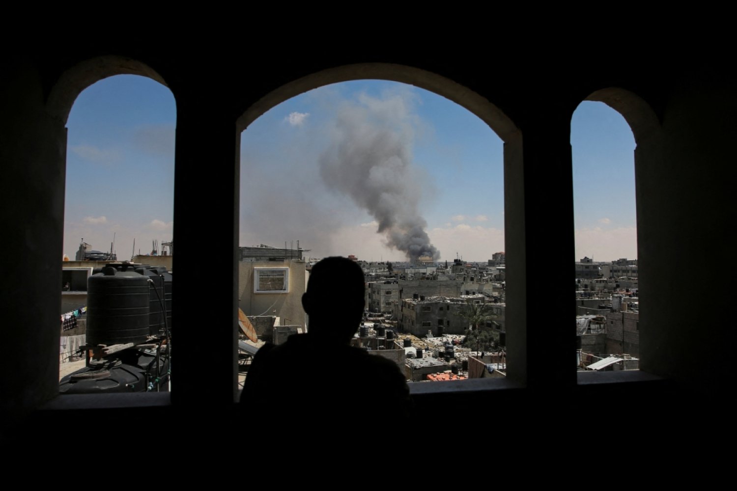 Refah'ın doğusundaki bir binada pencereden İsrail'in hava saldırısı düzenlediği bölgeye bakan bir Filistinli (Reuters)
