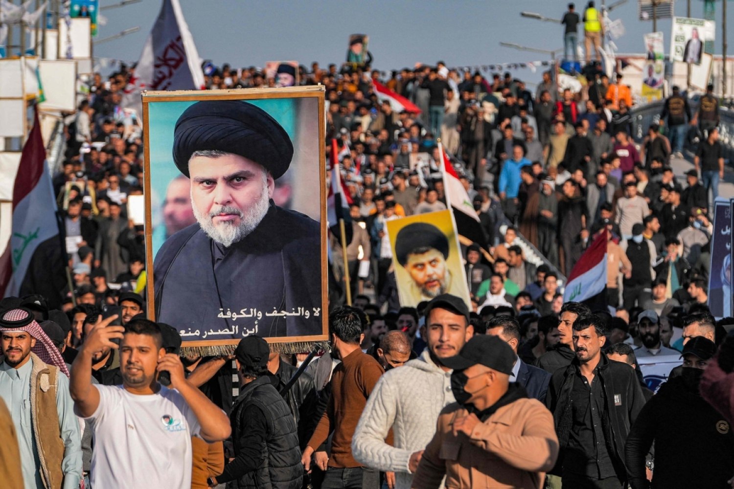 Necef kentinde geçtiğimiz yıl düzenlenen yerel seçimlerin boykot edilmesi çağrısıyla düzenlenen gösterilerde Sadr'ın portreleriyle yürüyen Mukteda es-Sadr'ın destekçileri, 14 Aralık 2023 (AFP)