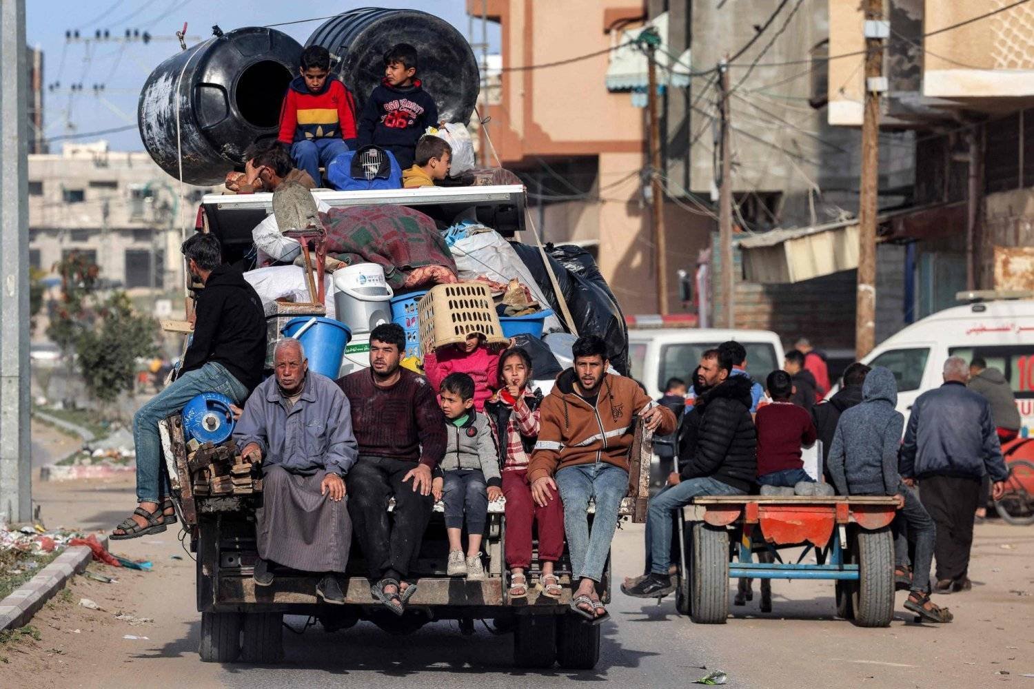 Refah'tan Gazze Şeridi'nin orta kesimine doğru bir kamyonetin arkasında yolculuk eden Filistinli bir aile (AFP)