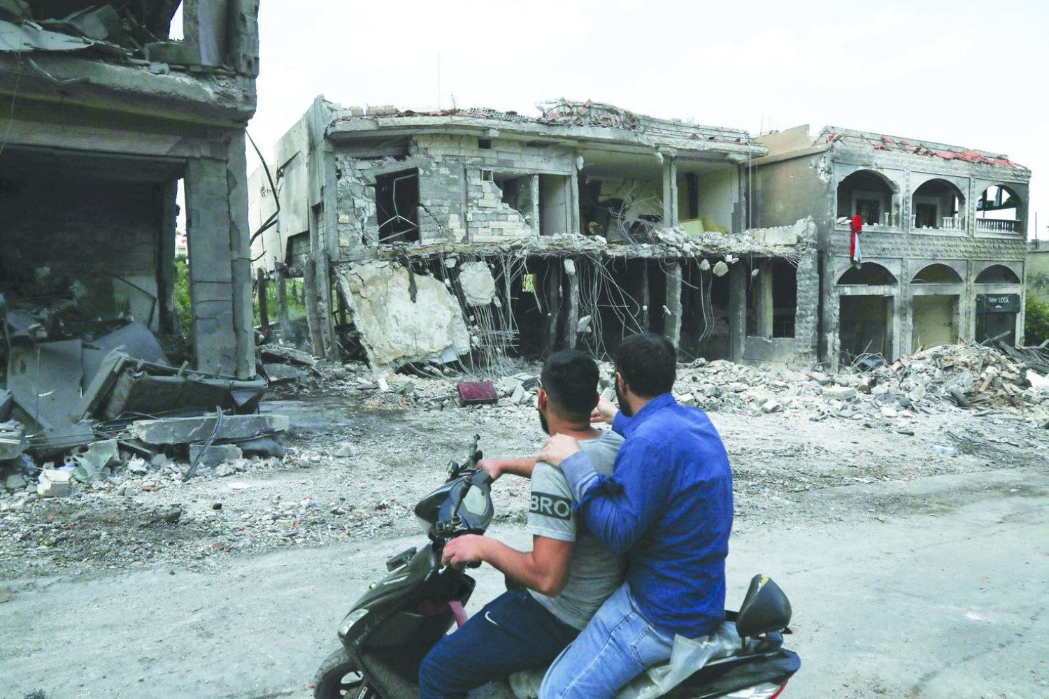 Lübnan'ın güneyindeki Meys el-Cebel sınır kasabasında İsrail hava saldırısında hasar gören binaları inceleyen iki adam (AFP)